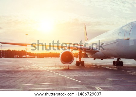 View of the wing and engine of a long-range passenger aircraft, evening airport at sunset
