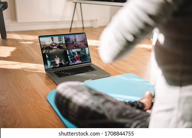 View Of A Woman Conducting Virtual Fitness Class With Group Of People At Home On A Video Conference. Fitness Instructor Taking Online Yoga Classes Over A Video Call In Laptop.