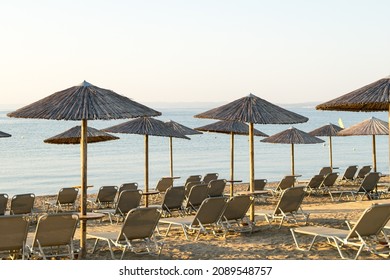 View Of Wooden Umbrellas And Sun Loungers On A Mediterranean Beach