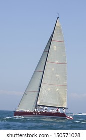 View of a yacht with white sail competing in team sailing event