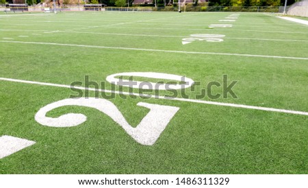 A view of the yard numbers on a football field, featuring the 20 yard line.