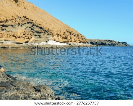 View of yellow cliffs and clear turquoise water in Playa Amarilla (Yellow Beach), situated at the foot of Montaña Amarilla (Yellow Mountain) on the Costa del Silencio in south Tenerife (Canary Islands, Spain).