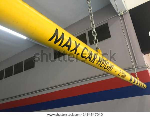 View of a\
yellow steel bar with the words MAX CAR HEIGHT 2.10m warning. It\
warns of the car park entrance height limit\
