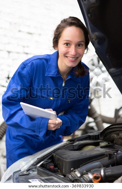 View of a Young attractive woman mechanic working\
at the garage
