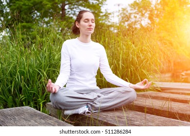 View of a Young attractive woman practising yoga in a park - Shutterstock ID 511286284
