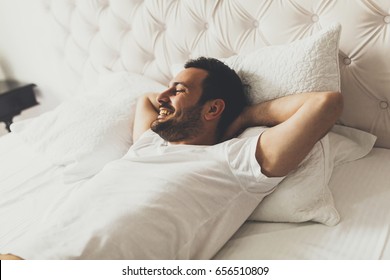 View at young handsome man lying on the bed and laughing