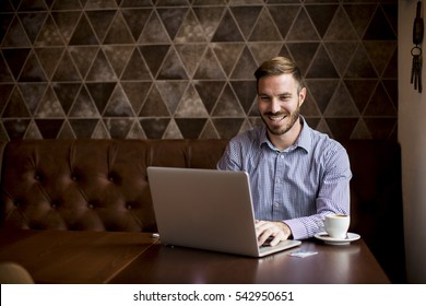 View At Young Man Sitting In Cafe And Using Laptop