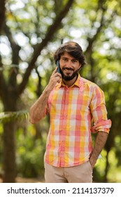View of young man using a smartphone at day time with a green park in the background. Mobile phone, technology, urban concept. High quality photo