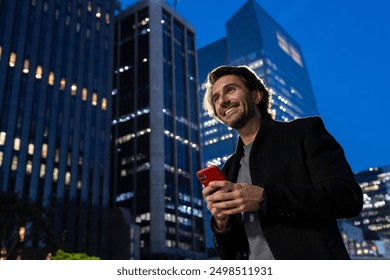 View of young man using a smartphone at night time with city view landscape in the background. High quality photo.  - Powered by Shutterstock