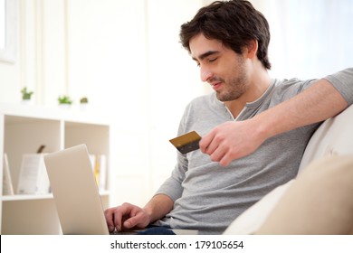 View of a Young relaxed man paying online with credit card in sofa - Shutterstock ID 179105654