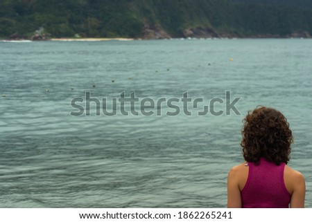 view of a young woman looking at the sea with selective focus and copy space
