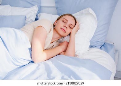 view of young woman sleeping on side in bed. girl sleeps with a blue blanket. view of a woman sleeping with eyes closed. - Shutterstock ID 2138829029