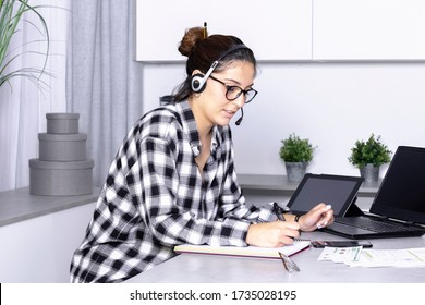 view of a Young woman working from home office. operator using laptop and take notes