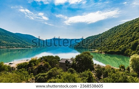 View of the Zhinvali Reservoir, a picturesque artificial reservoir in Georgia.Blue sky with white clouds.The reservoir is armed with mountains.Mountains are reflected in the water.Copy space.