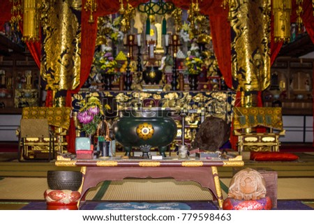 Viewed from the entrance, the elaborate, mysterious altar of an ancient Buddhist temple in Japan glitters with antique, golden religious objects on tatami straw mats.