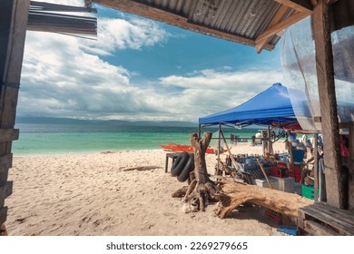 Viewed from within a shaded seating area,next to a drinks seller.A lazy,chilled out idyllic beach in the Philppine islands,with white,fine sand,clear blue sea,clean,un-polluted,serene and relaxing.