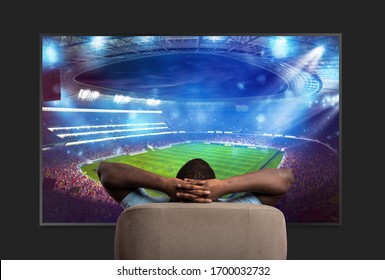 Viewer In Front Of A Large TV Relaxed On The Armchair At Home Watching A Sports Game