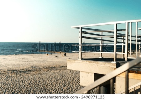 Viewing platform with a protective barrier. View of the sea and sandy beach. Stainless steel balustrade