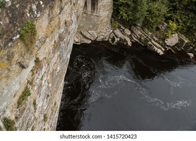 A viewpoint looking down off the side of a stone bridge. a place where people thinking of suicide may jump. cold dark water looms below. mental health problems.