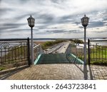 A viewpoint offers a panoramic view of a river and a busy highway lined with vehicles beneath dramatic skies.