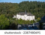 Views of Clervaux commune with town status in northern Luxembourg and green forest, capital of  canton of Clervaux, white castle on sunset