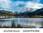 Views of the Rocky Mountains snow covered mountain tops from across a still smooth lake with majestic clouds overhead in Grand Lake, Colorado, USA.