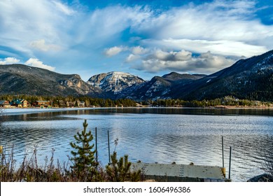 Views Of The Rocky Mountains Snow Covered Mountain Tops From Across A Still Smooth Lake With Majestic Clouds Overhead In Grand Lake, Colorado, USA.