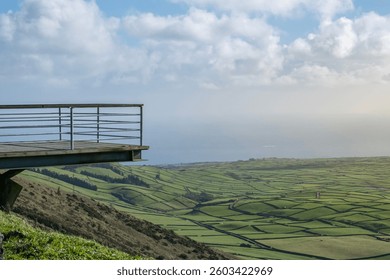Views from a viewpoint of green fields and the ocean. Stunning panoramic view from Serra de Cume, Terceira, showcasing lush green patchwork fields leading to the vast Atlantic Ocean