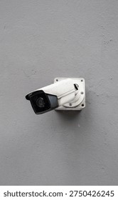 A vigilant security camera mounted on a smooth concrete wall keeps a watchful eye, symbolizing modern surveillance and safety measures in urban environments — its sleek design blends seamlessly with the minimalist architecture, ensuring protection without compromising aesthetics