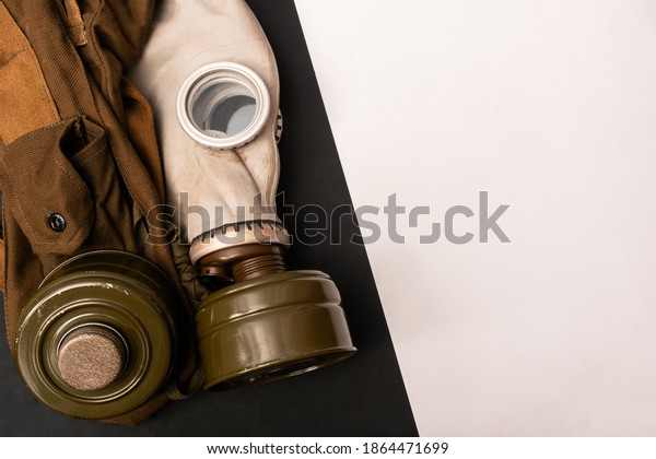 Vignetted image\
of dirty gas mask with filter and army pouch, belt kit  on black\
and white diagonally divided grunge background with space for text,\
inscription. Copy space. Top view\
