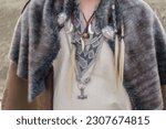 Viking man ornaments, Viking fang pendants and Viking chains with metal animal heads, the hammer etc... He also wears a collar of shaggy animal hair. All in the foreground on the man