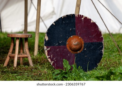 A Viking shield leaning against a tent peg of an encampment.