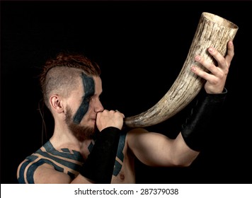 Viking With Tattoos Holding Horn On Black Background.