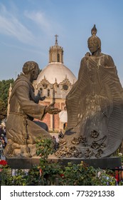 VILLA OF GUADALUPE, MEXICO CITY, DECEMBER 02, 2017. Sculpture Of Juan Diego And Fray Juan De Zumarraga In The Gardens Of The Villa Of Guadalupe. At The Background We Can See The Pocito Church. 