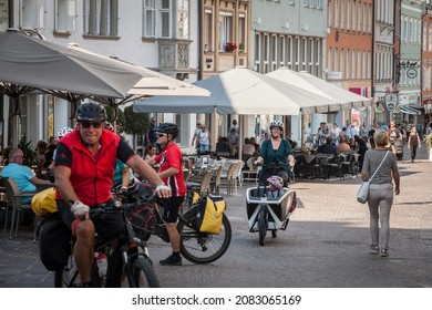 VILLACH, AUSTRIA - SEPTEMBER 13, 2021: Selective blur on various cyclists biking in the city center of Villach, Carinthia, including a mother carrying a child on a children bicycle cart. 