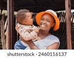 village african mother and baby standing at the entrance of the shack, township village in south africa