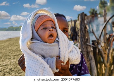 village african people, young girl holding a yawning sleepy baby, unwanted teenage pregnancy, braided hair - Powered by Shutterstock