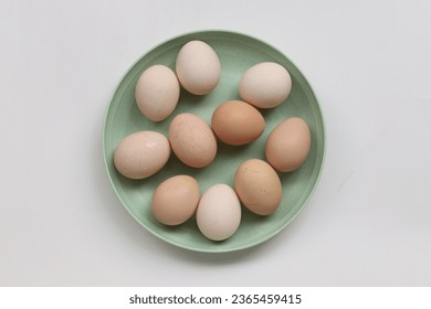 Village chicken eggs, it's well known in Indonesia named as telur ayam kampung, placed on plate isolated on white background, top view - Shutterstock ID 2365459415