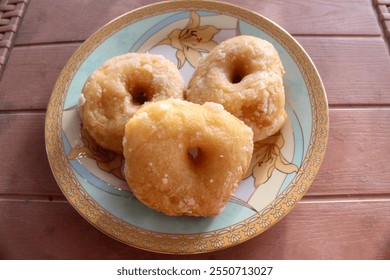 Village donuts or old-school donuts, traditional Indonesian donuts, served with a sprinkling of ground granulated sugar, on a patterned plastic plate, isolated on a chocolate plastic table. - Powered by Shutterstock