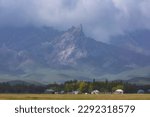 village at the foot of the mountains with rocky peaks in the clouds, Beautiful landscapes of southern Kazakhstan in the Karatau mountains near the Kelinshektau ridge