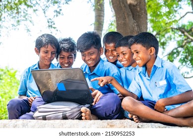 Village group of kids in uniform with using laptop while sitting on near paddy field - concept of education, development and technology.