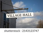 A Village Hall sign hanging from a local community building which is a meeting place for the residents of a small English neighbourhood