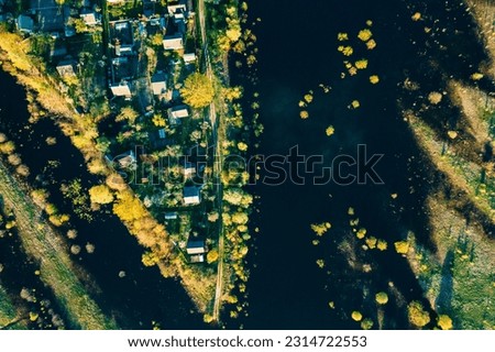 Village and inundation river. Aerial View Green Forest Woods And River Landscape In Sunny Spring Summer Day. Top View Of Nature, Bird's Eye View. Trees Standing In Water During Spring Flood