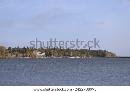village and moored boats viewed from across a lake under blue skies