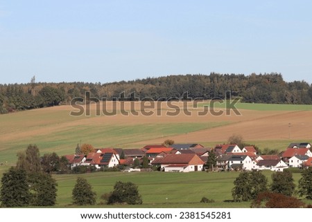 Similar – A tractor turns mown hay in a field in a small community