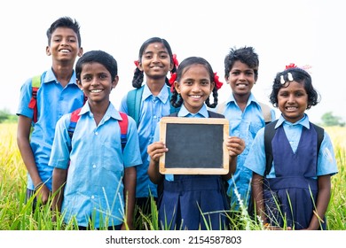Village teenage kids showing empty slate board by looking at camera at farmland - concept of advertisement, education and friendship - Shutterstock ID 2154587803