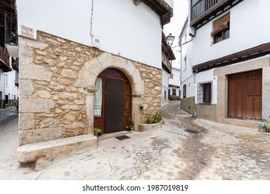 Villanueva De La Vera, Spain - March 08, 2021: An Old Traditional House With Stone Archway At The Front Door And Granite Stone Facade With Some Small Potted Plants Outside