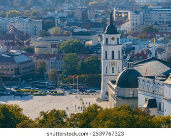 Vilnius Cathedral and its bell tower are seen from above, surrounded by a mix of historical and modern buildings, with people in the square below. - Powered by Shutterstock