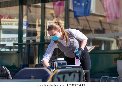 Vilnius, Lithuania - April 30 2020: Waitress With A Mask Disinfects The Table Of An Outdoor Bar, Café Or Restaurant, Reopening After Quarantine Restrictions, During Coronavirus Or Covid Outbreak