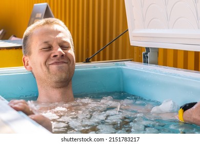 Vilnius, Lithuania - April 30 2022: Boy or man with closed eyes smiling and bathing in the cold water among ice cubes. Wim Hof Method, cold therapy, breathing techniques, yoga and meditation